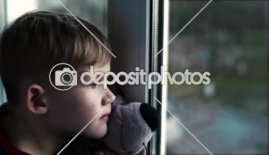 Küçük çocuk pencereden bakarak yakınındaki ayı ile üzgün küçük çocuk yalnız çocuk