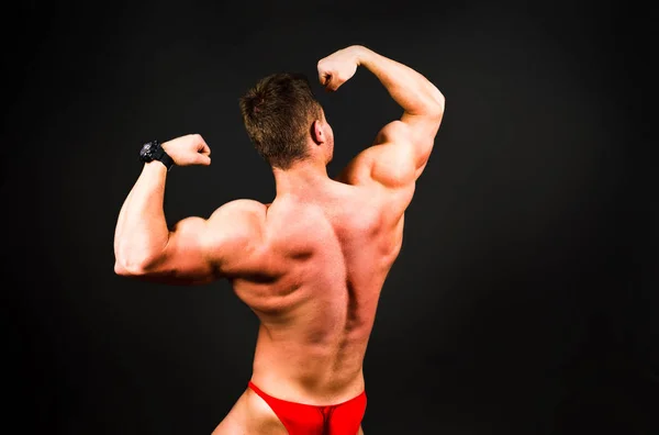 Bodybuilder Lässt Muskeln Vor Dunkel Strukturiertem Hintergrund Spielen — Stockfoto