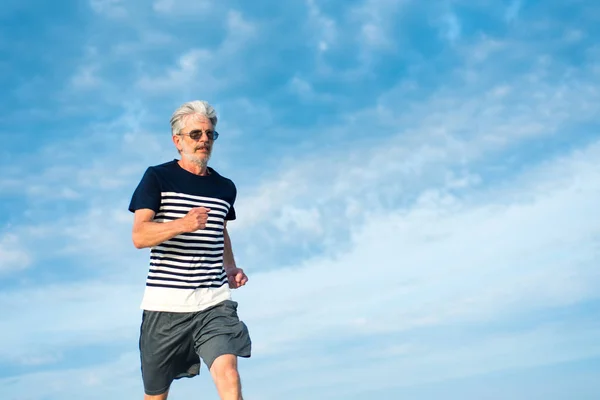 Uomo Anziano Che Corre Sulla Spiaggia Contro Cielo Nuvoloso — Foto Stock
