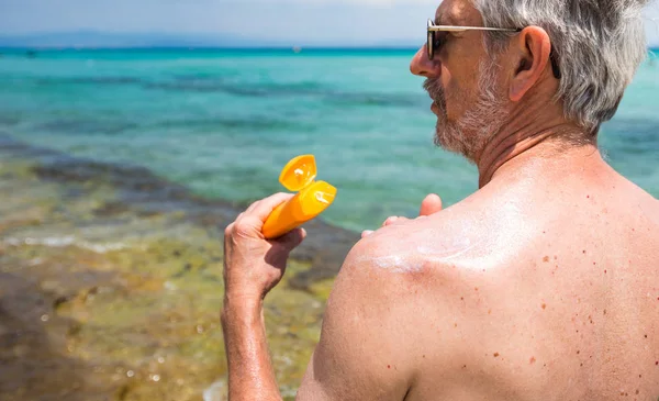 シニア男適用日焼け止めは夏の休暇に表示 — ストック写真