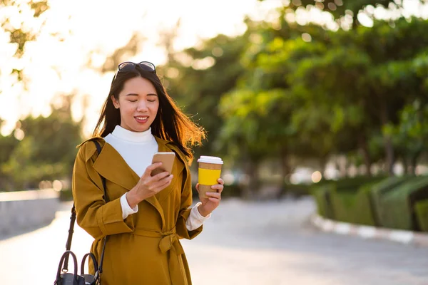 愉快的女孩使用电话和有一杯咖啡户外 — 图库照片