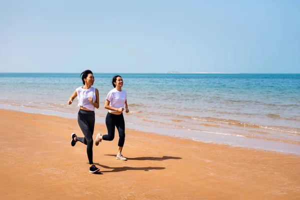 在阳光灿烂的日子里 女性朋友们在海滩上奔跑 — 图库照片