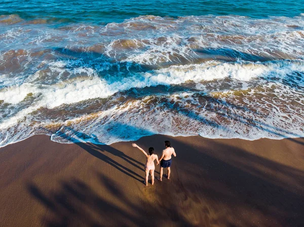 Coppia che si tiene per mano sulla spiaggia aerea — Foto Stock