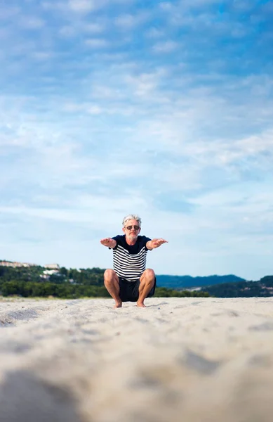 Uomo anziano che fa esercizi di stretching sulla spiaggia — Foto Stock