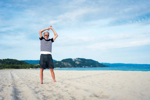 Senior man doing stretching exercises on the beach — Stock Photo, Image