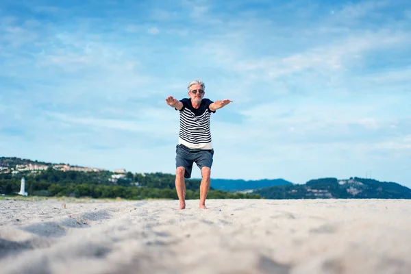 Senior man doing stretching exercises on the beach — Stock Photo, Image