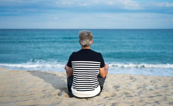 Uomo anziano meditando sulla spiaggia — Foto Stock