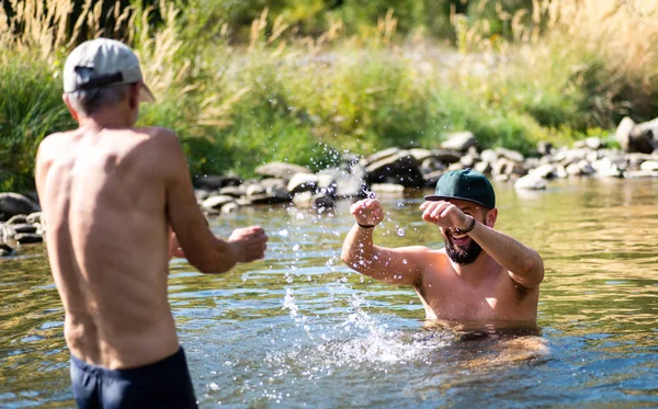 Father and son splashing each other with water in the river — Stock Photo, Image