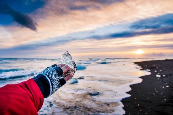 Reisender hält Eisbrocken am Diamantenstrand in Island — Stockfoto