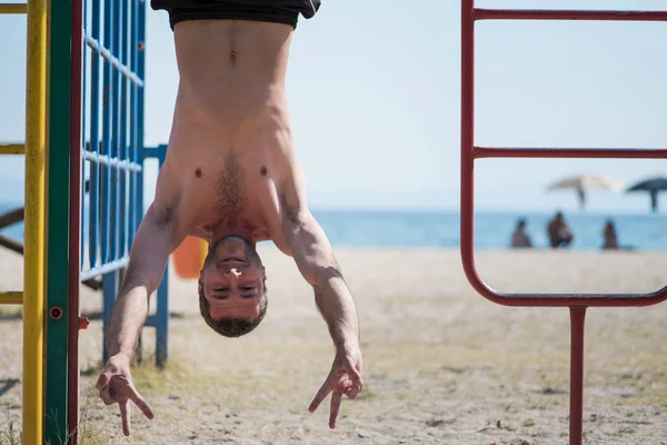 Man hanging upside down at kids playground — Stock Photo, Image