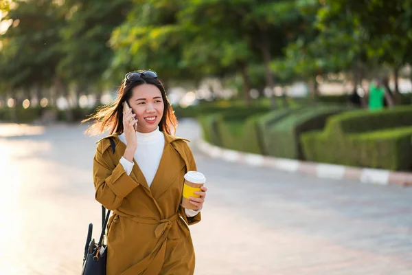 Bir fincan kahve içen ve dışarıda telefon kullanan bir kadın. — Stok fotoğraf