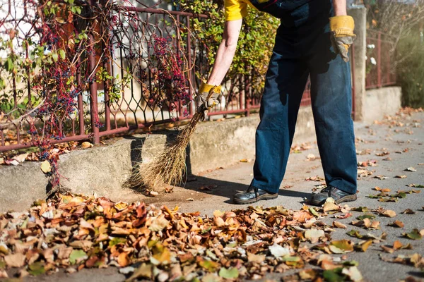 Homem vassoura a rua para recolher folhas caídas — Fotografia de Stock