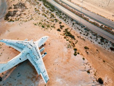 Abandoned airplane in the in the Umm Al Quwain desert in the emirate of the United Arab Emirates aerial view at sunrise clipart