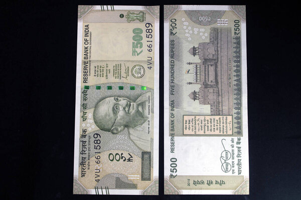 Indian currency. 500 rupee note with Indian coins. Indian currency isolated on black background.