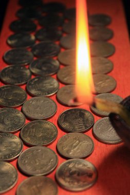 Mum ışığıyla Hint parası. Kırmızı arka planda izole edilmiş 1, 2, 5, 10 Hint Rupisi metal para yığını. Finansal, ekonomik