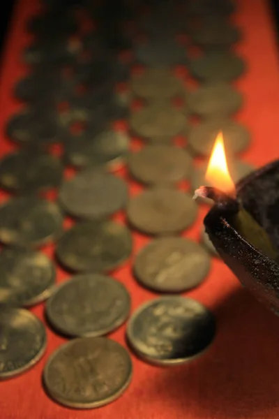 Indian rupee coins with candle light. Stock pile of 1, 2, 5, 10 Indian rupee metal coin currency isolated on red background. Financial, economy