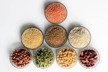 Beyaz zemin üzerinde bulunan baklagil koleksiyonu (nohut, yeşil bezelye, pembe mercimek, Hint mercimeği, kırmızı fasulye, yeşil mung fasulyesi, kuru bezelye, Güvercin Bezelyesi, Kırmızı Böbrek, Fenugreek Tohumu, Yulaf ezmesi).