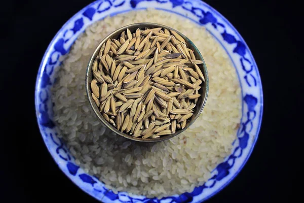 Rice grains in a bowl on white rice texture background. Macro background of rice grains. Basmati rice on a pile isolated on black background.