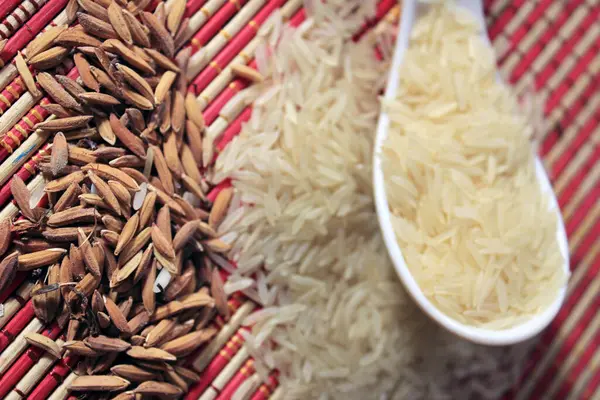 Rice grains in a white plastic spoon on multi color texture background. Macro background of white rice. Basmati rice on a pile isolated on colorful pattern background.