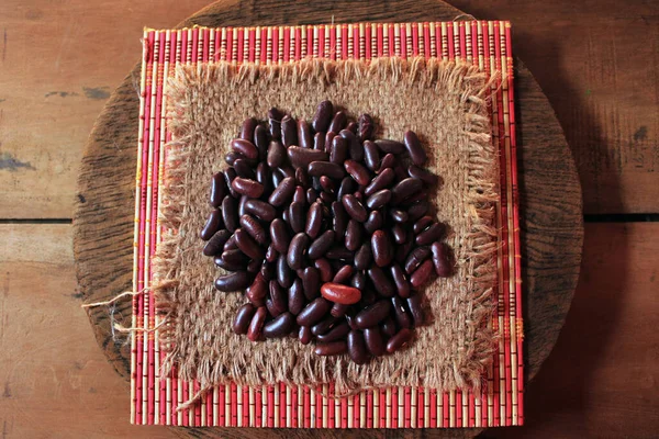 Red kidney beans isolated on wooden background. Closeup of Multiple red kidney beans still-life display with sack texture display.