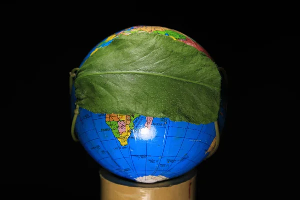 Covid19状況中の地球の再生 世界のコロナウイルスとCovid 19パンデミックの概念 緑の葉で保護されたグローブ 概念的な写真 黒い背景に隔離された地球の地球 — ストック写真