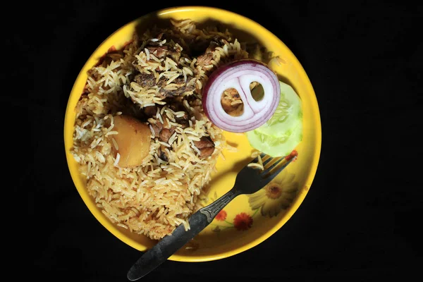 おいしいインドの鶏Biriyani黒の背景に隔離された黄色のプレート上に インドのチキンBiriyaniキュウリとカレー食品 玉ねぎ インドのチキンティッカ ビリヤニカレー — ストック写真