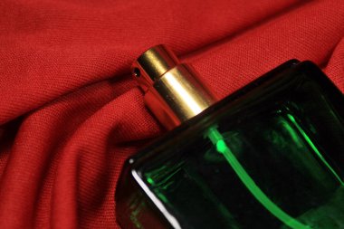 Kırmızı zemin üzerinde kadın aksesuarları olan yeşil renk parfüm şişesi..