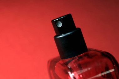 Kırmızı renkli erkekler, kırmızı ipek arka planda izole edilmiş parfüm şişesi. Siyah şapkalı kırmızı parfüm şişesi, doğal sprey..