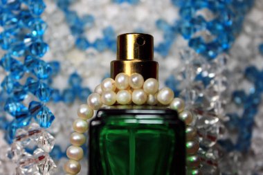 Kırmızı arka planda, kadın aksesuarlarıyla izole edilmiş renkli plastik poşetlere yeşil renk parfüm şişesi..