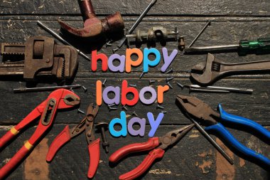 Ahşap arka planda, inşaat aletleriyle kırmızı renkli İşçi Bayramı metni. İşçi bayramı tabelası. Mutlu İşçi Bayramı - vida yazma.