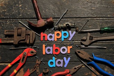 Ahşap arka planda, inşaat aletleriyle kırmızı renkli İşçi Bayramı metni. İşçi bayramı tabelası. Mutlu İşçi Bayramı - vida yazma.