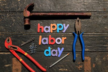 Ahşap arka planda, inşaat aletleriyle kırmızı renkli İşçi Bayramı metni. İşçi bayramı tabelası. Mutlu İşçi Bayramı - vida yazma.