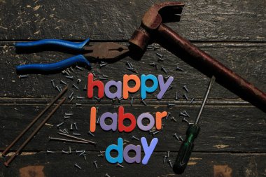 Ahşap arka planda, inşaat aletleriyle kırmızı renkli İşçi Bayramı metni. İşçi bayramı tabelası. Mutlu İşçi Bayramı - vida yazma.