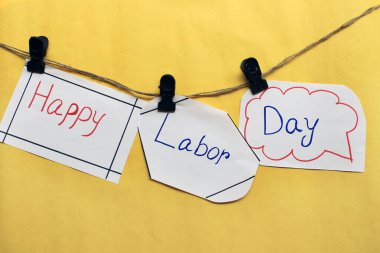 İple sarkan parlak sarı arkaplanlı İşçi Bayramı mesajın kutlu olsun. İşçi bayramı tabelası. Kağıt konuşma baloncukları ve sarı arkaplanda asılı duran Mutlu İşçi Bayramı metni..