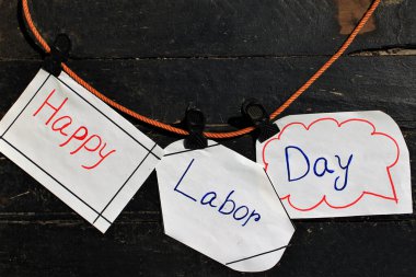 Ahşap arka planda iple asılı İşçi Bayramı metnin kutlu olsun. İşçi bayramı tabelası. Kağıt konuşma baloncukları ve üzerinde 