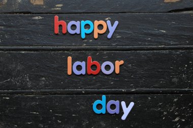 Ahşap arka planda, inşaat aletleriyle kırmızı renkli İşçi Bayramı metni. İşçi bayramı tabelası. Mutlu İşçi Bayramı - vida yazma.