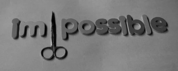 Self belief and positive concept, scissors cut off the word Impossible to read possible. From impossible to the possible. Cutting out the word Impossible to Possible.