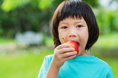 Yeşil doğası olan bir elma yiyen çocuklar.