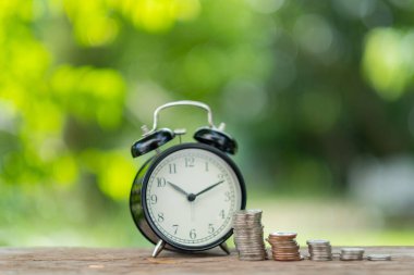 Tahta arka planda bozuk paraları olan minyatür ev modeli.