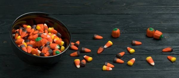 Candy for Halloween. Autumn mix Orange pumpkin and candy corn  Trick or treat and Happy Halloween. Dark Natural wooden background.