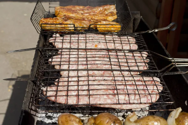 Cozinhar carne e salsichas na grelha . — Fotografia de Stock