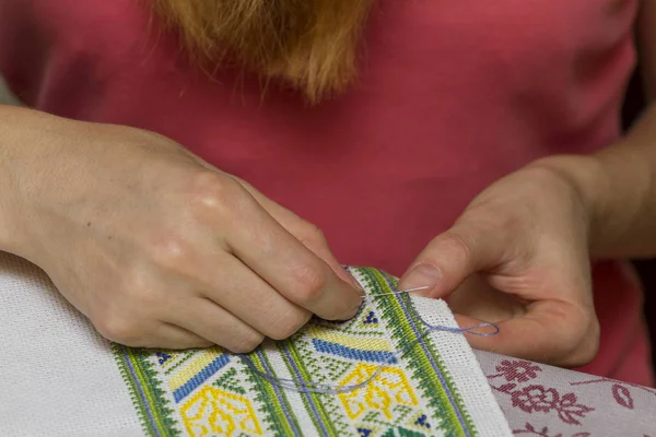 Close up of woman embroidering traditional pattern on fabric