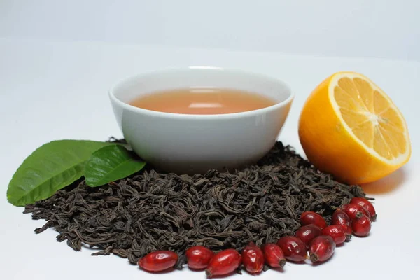 Tea in drinking bowl with dog rose berries and orange