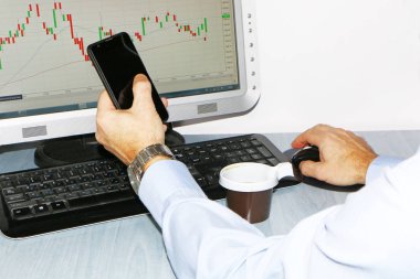 Yakın çekim-tablo bir monitör için bir bilgisayar, bir fincan kahve, bir akıllı telefon, bir hisse senedi grafiği