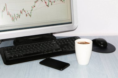 Yakın çekim-tablo bir monitör için bir bilgisayar, bir fincan kahve, bir akıllı telefon, bir hisse senedi grafiği