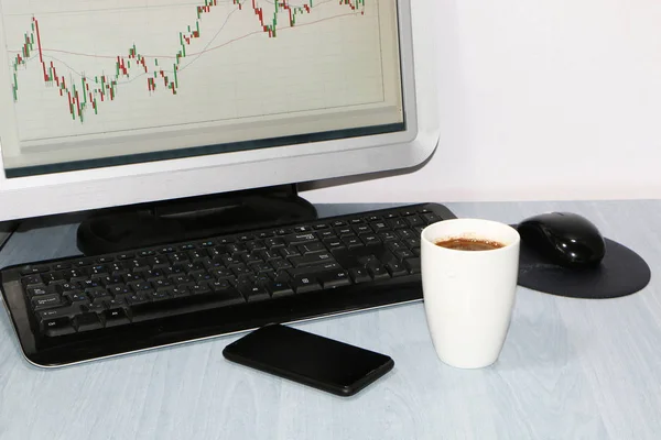 クローズ アップ コンピューター コーヒー カップ スマート フォン 株価チャートのためのモニターのテーブルの上 — ストック写真