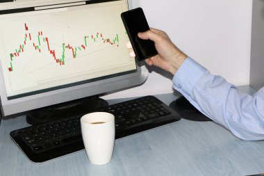Yakın çekim-tablo bir monitör için bir bilgisayar, bir fincan kahve, bir akıllı telefon, bir hisse senedi grafiği