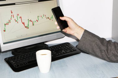 Yakın çekim-tablo bir monitör için bir bilgisayar, bir fincan kahve, bir akıllı telefon, bir hisse senedi grafiği