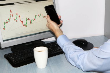 Yakın çekim-tablo bir monitör için bir bilgisayar, bir fincan kahve, bir akıllı telefon, bir hisse senedi grafiği
