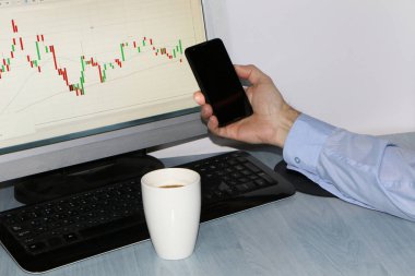 Yakın çekim-tablo bir monitör için bir bilgisayar, bir fincan kahve, bir akıllı telefon, bir hisse senedi grafiği